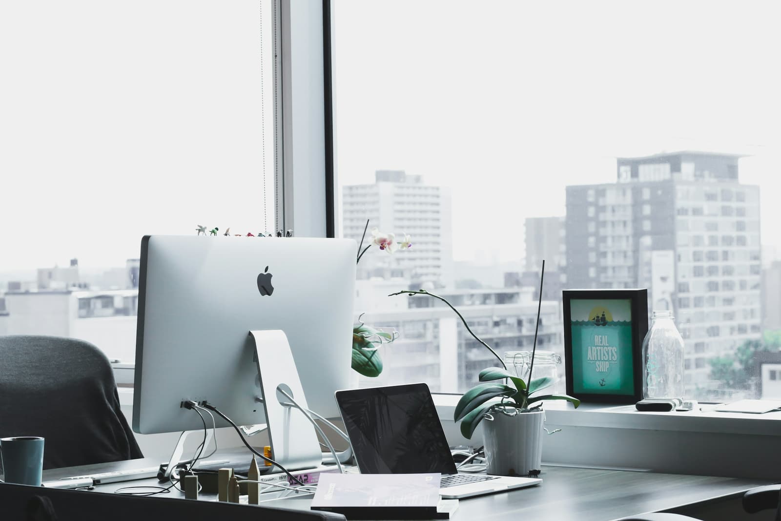 An iMac workstation beside a window in a bright office